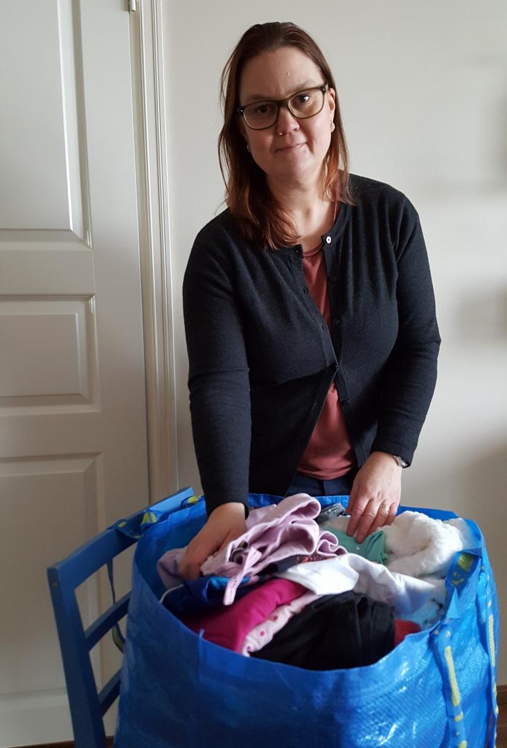 Bild på Annika med en stor kass med kläder som hon ska donera till välgörenhet.